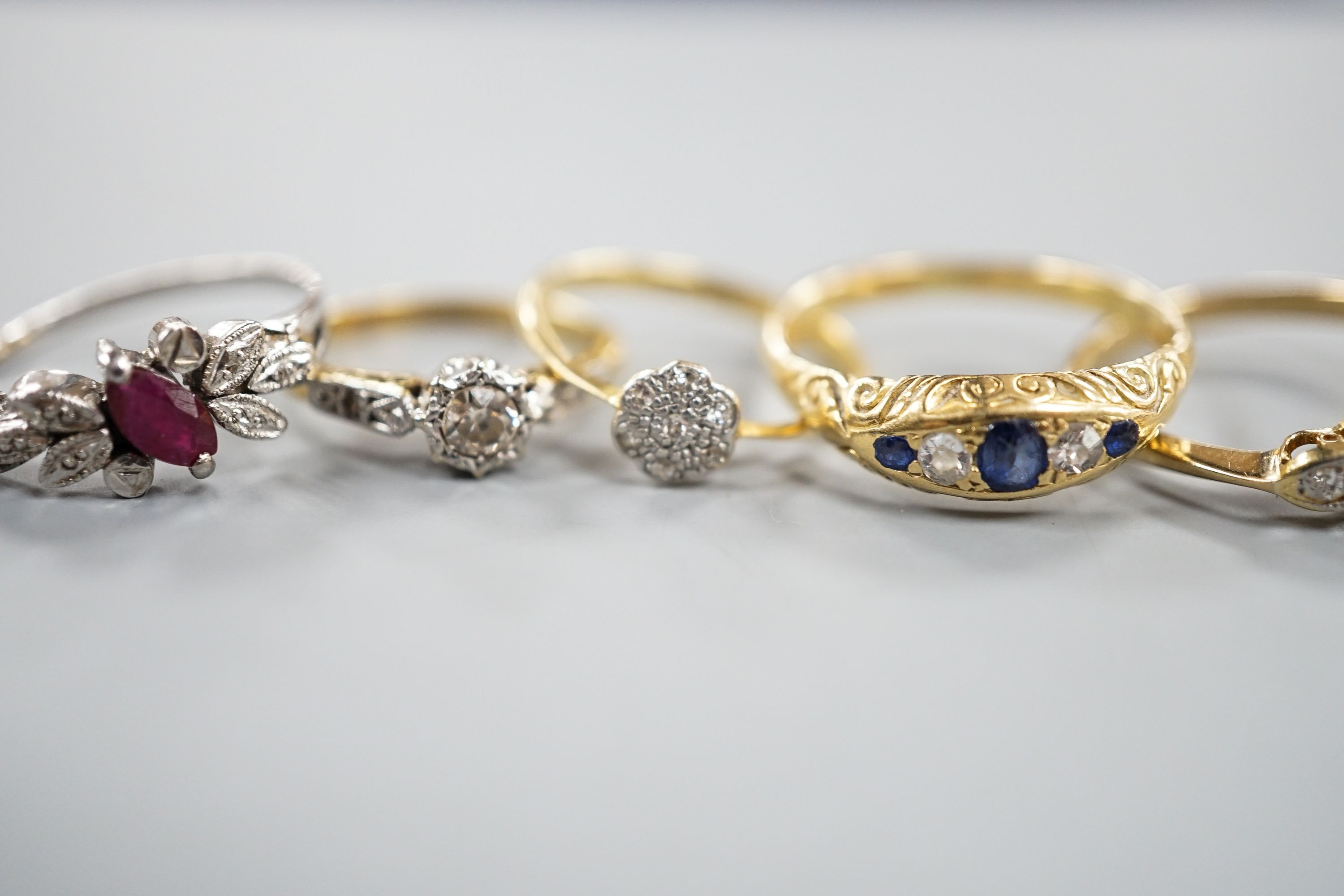 Two 18ct and diamond rings, including small cluster and single stone, sizes L & H, an 18ct sapphire and diamond ring, size O, gross 7.3 grams and two other yellow or white metal and gem set rings, gross 3.6 grams.